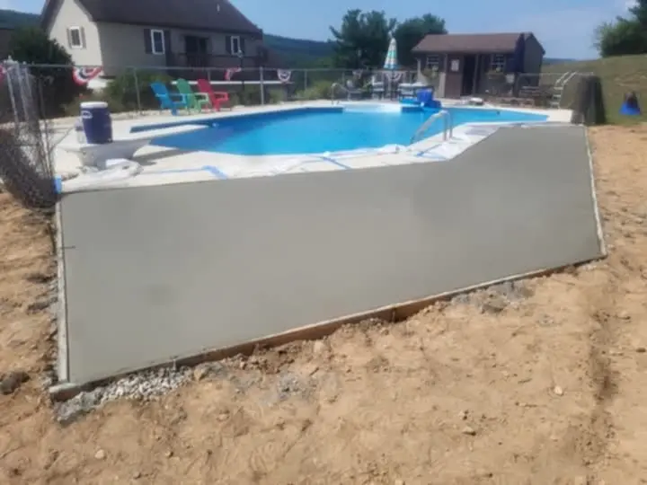 Freshly poured concrete deck surrounding a beautiful in-ground pool by Rhinesmith Construction