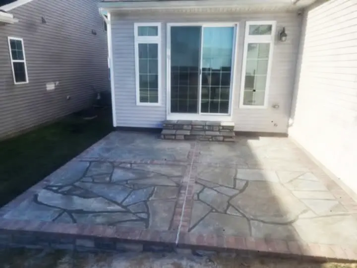 Beautiful custom stone patio with natural stone shapes and brick accents by Rhinesmith Masonry